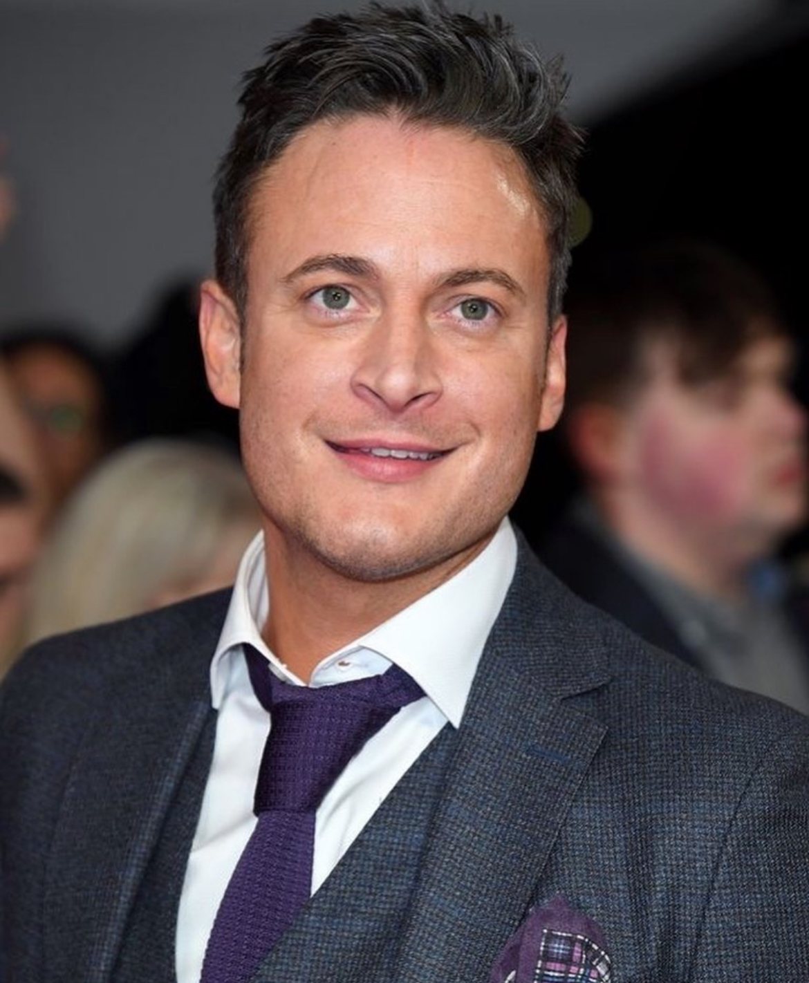 Gary Lucy, British actor, smiling in a three-piece suit at a red carpet event